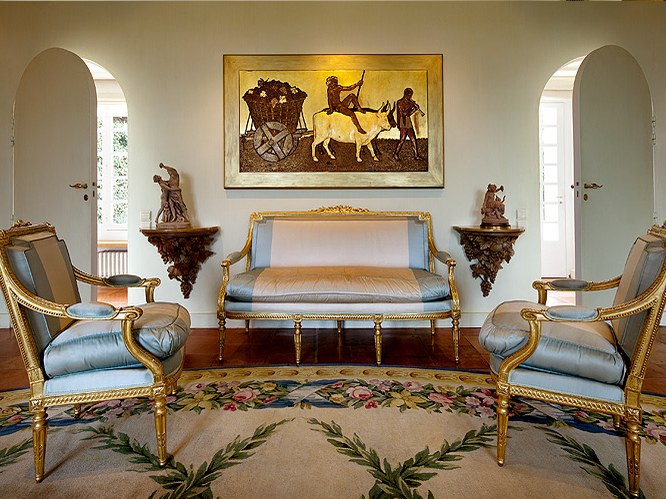 Sofa, armchairs, wall painting, decorative sculptures, floral rug, arched doorway.