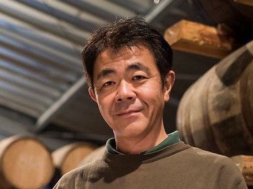 The founder of Chichibu Distillery, stands among aging barrels in his whisky warehouse.
