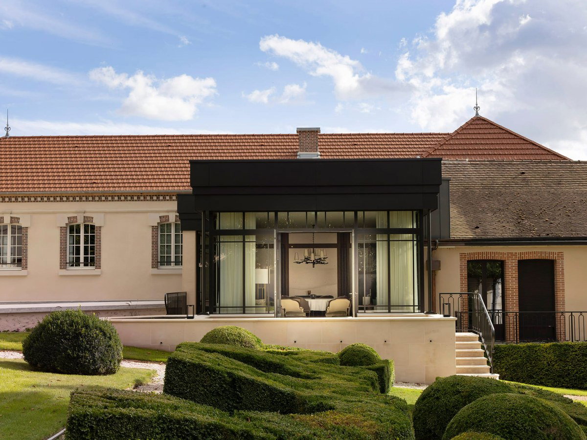 The exterior of Maison Billecart-Salmon's estate features a classic French country manor with a terracotta tile roof, cream walls, and brick details.