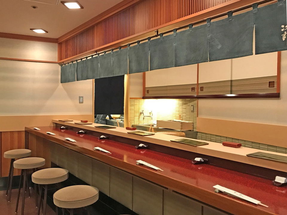 Sukiyabashi Jiro Roppongi offers a pristine sushi counter experience with its polished red wood and noren curtain.