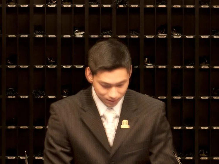 Hotel staff member at a reception desk with cubby storage behind.