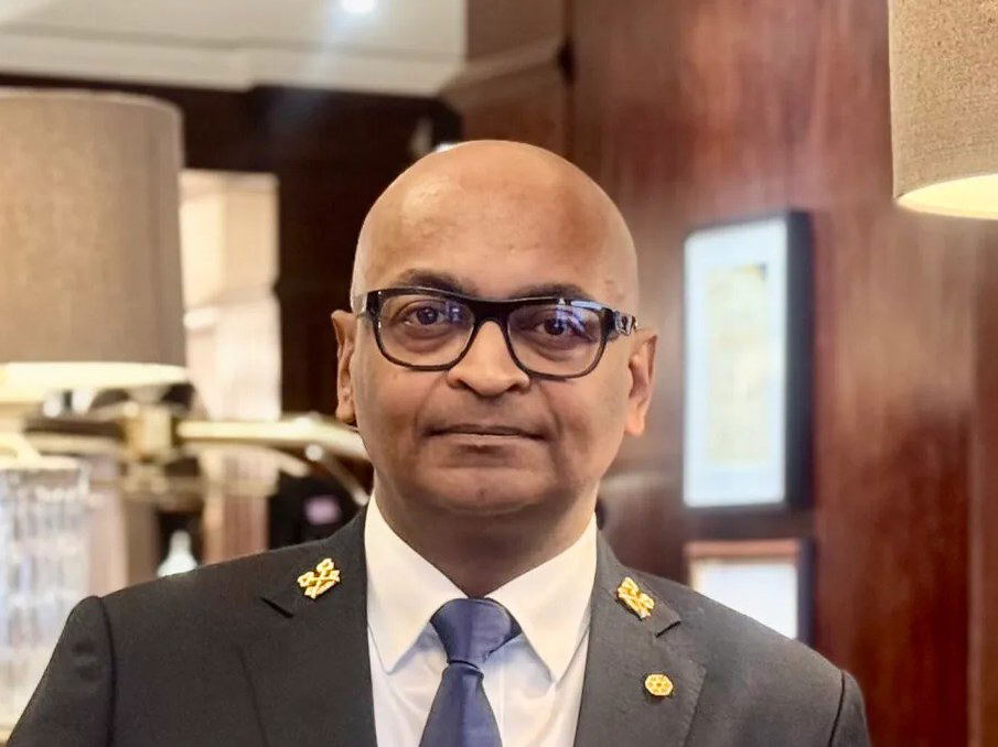 A Les Clefs d'Or concierge stands at a hotel desk, representing a key restaurant reservation channel.