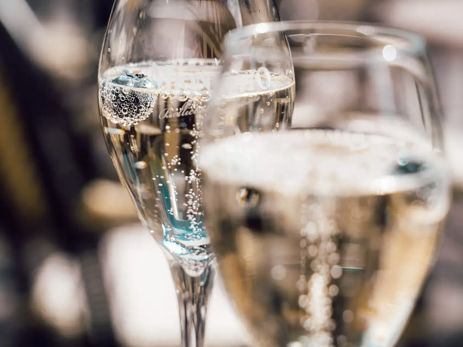 A close-up of a champagne flute filled with sparkling wine showing active carbonation bubbles rising through the clear liquid.