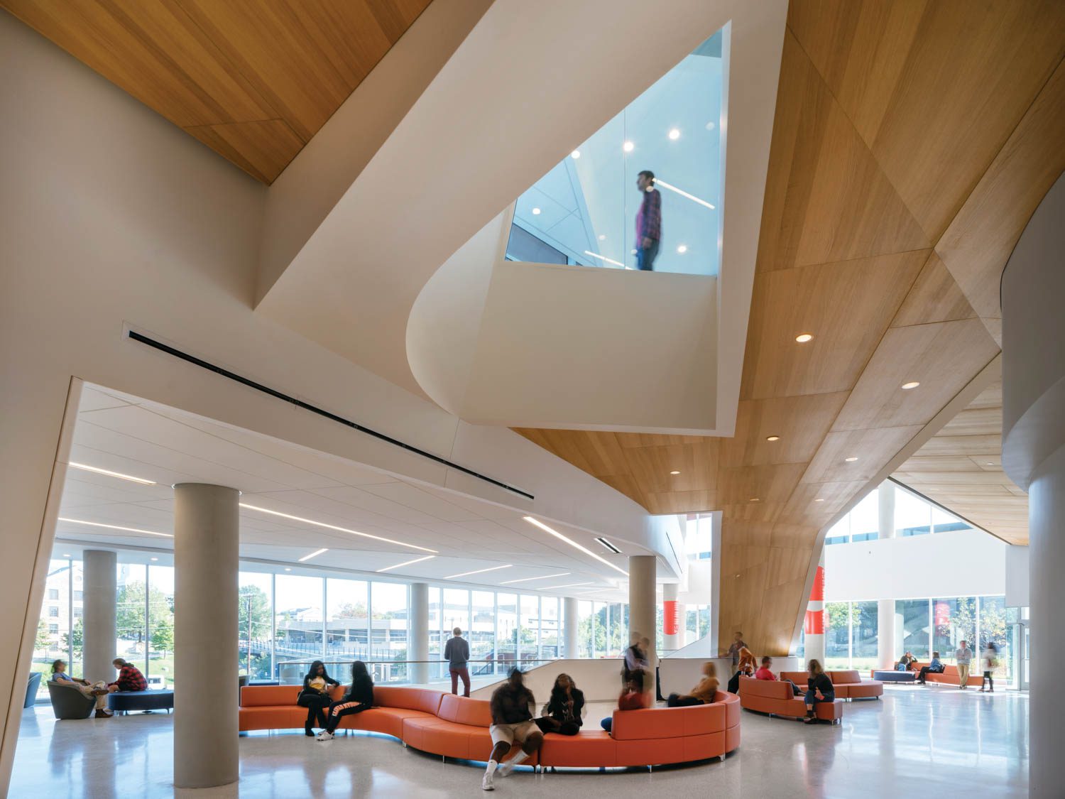 Architecture and Facilities feature vibrant orange, curved lounge seating throughout the expansive open space.