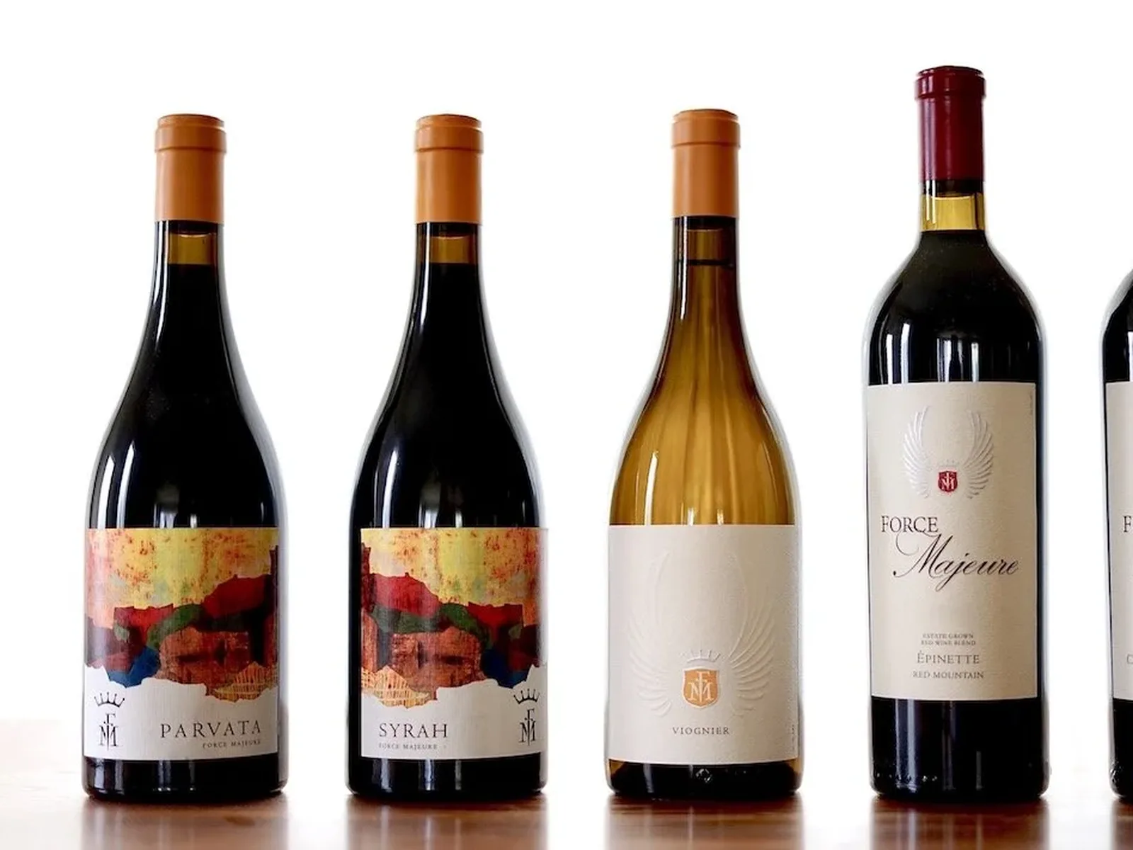 Four wine bottles displayed against a white background, showing red and white wines from Force Majeure winery with distinctive labels.