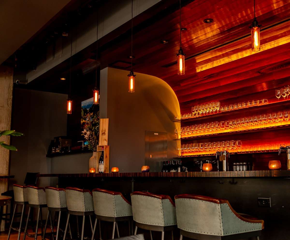 The Tasting Room features a warm, inviting glow illuminating its rows of wine glasses.