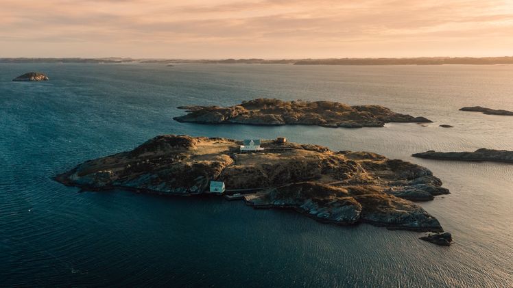 Aerial view of rocky islands in turquoise water at sunset, matching the Condé Nast Traveler article's explicit attestation about Norway's newest islan
