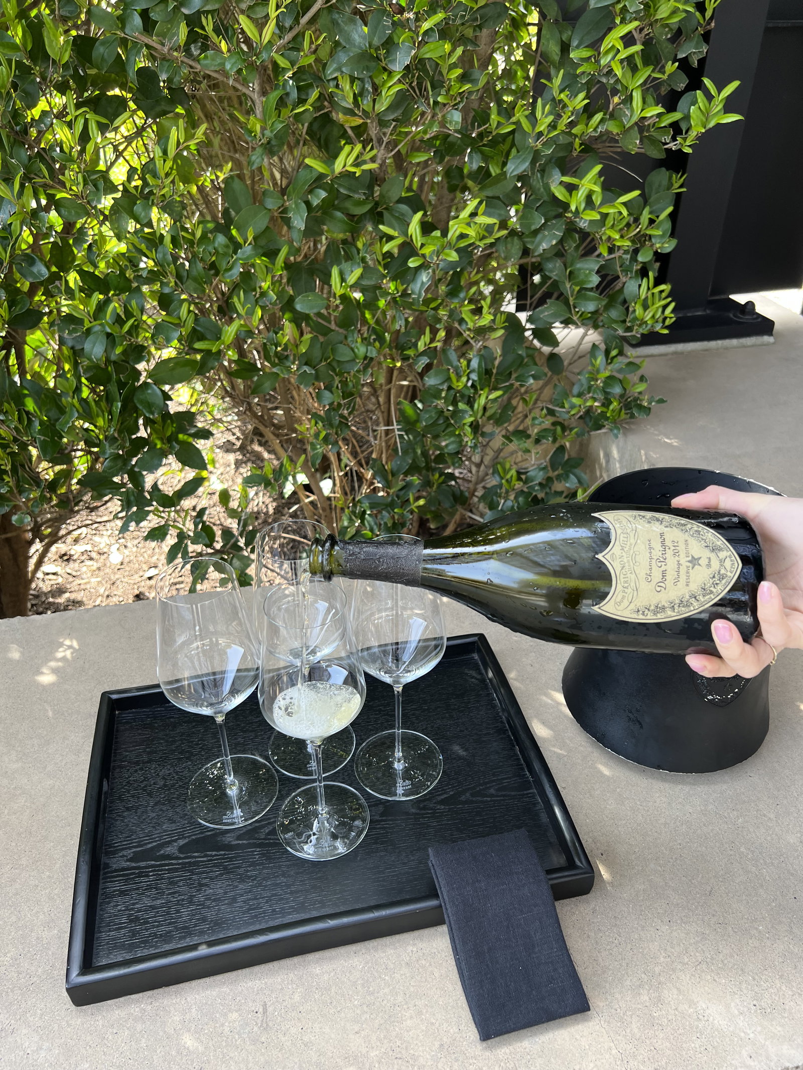 Someone pouring champagne into four glasses