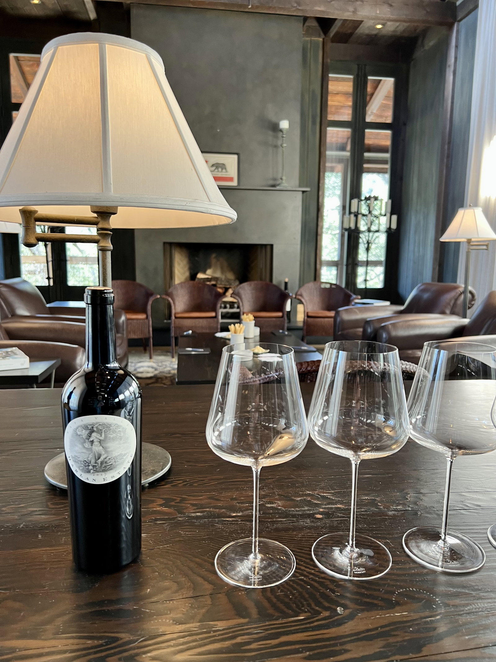 a bottle of wine and two glasses by a fireplace