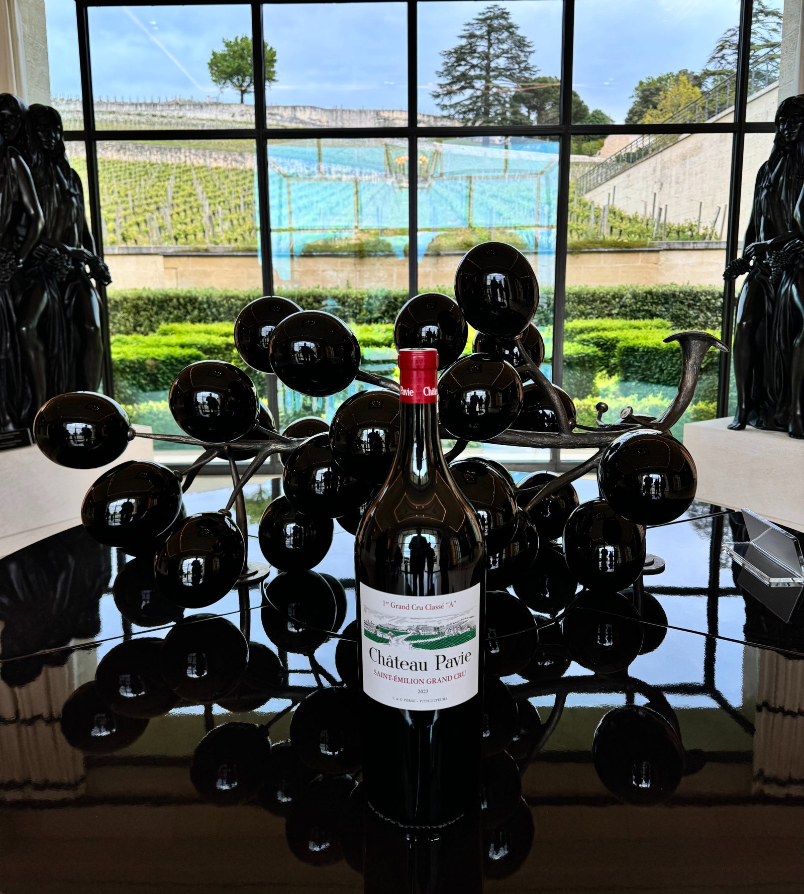 an entrance to a winery with black statues and a wine bottle