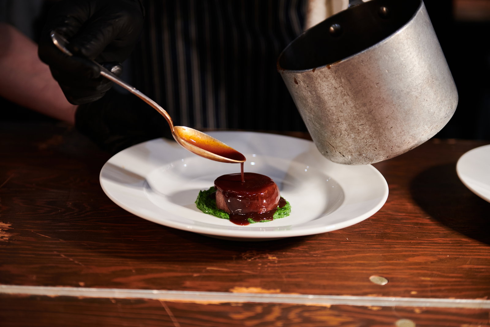 a fine dining plate with a sauce being poured