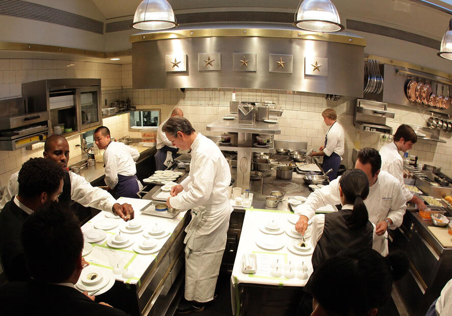 Chefs and staff work busily in a compact but modern kitchen