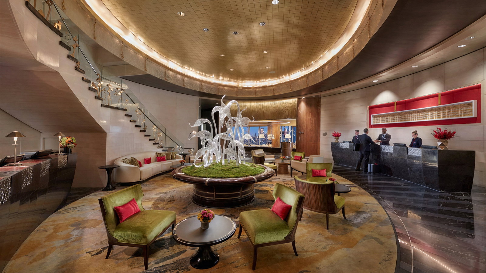 Elegant hotel lobby with a glass sculpture centerpiece, luxurious seating, and check-in desks. Warm lighting and curved staircase enhance ambiance.