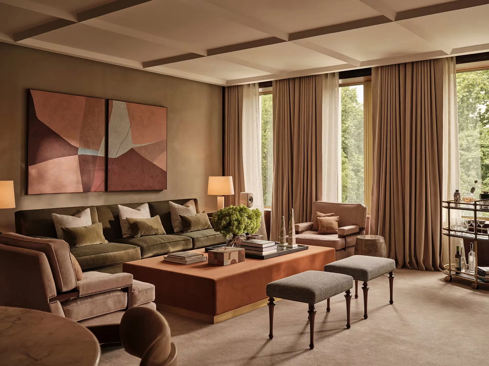 Elegant living room of grand premier grosvenor suite at The Chancery Rosewood with olive sofa, abstract art, soft lighting, beige curtains, and a wooden table. Neutral tones create a cozy ambiance.