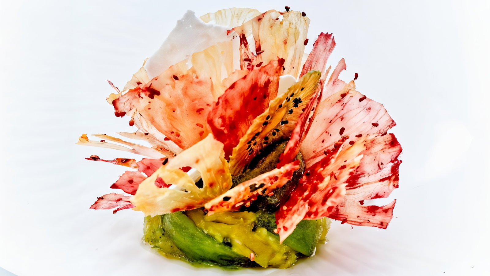 Colorful food art piece on white background, with avocado base and delicate red-tinted, petal-like slices arranged beautifully.