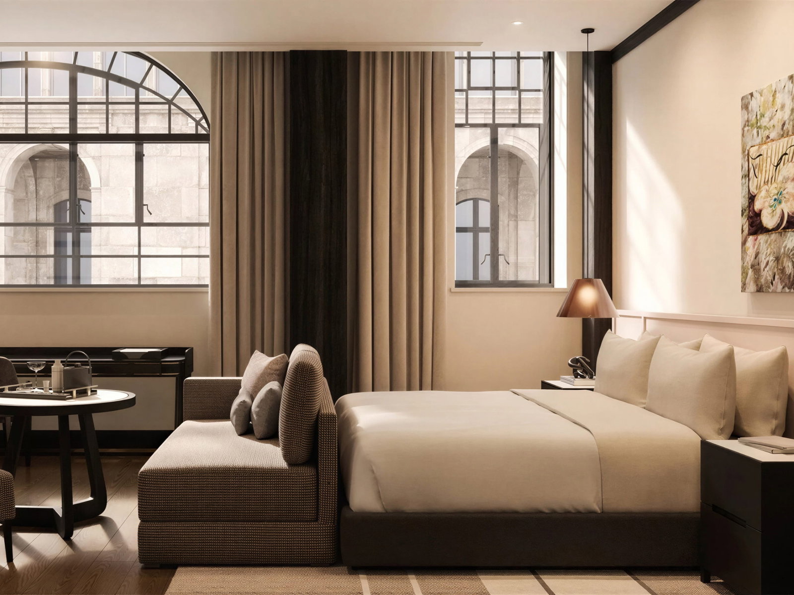 Deluxe Room at Capella Sydney with a beige bed, sofa, and table under large arched windows. Soft lighting and a floral painting create a cozy ambiance.