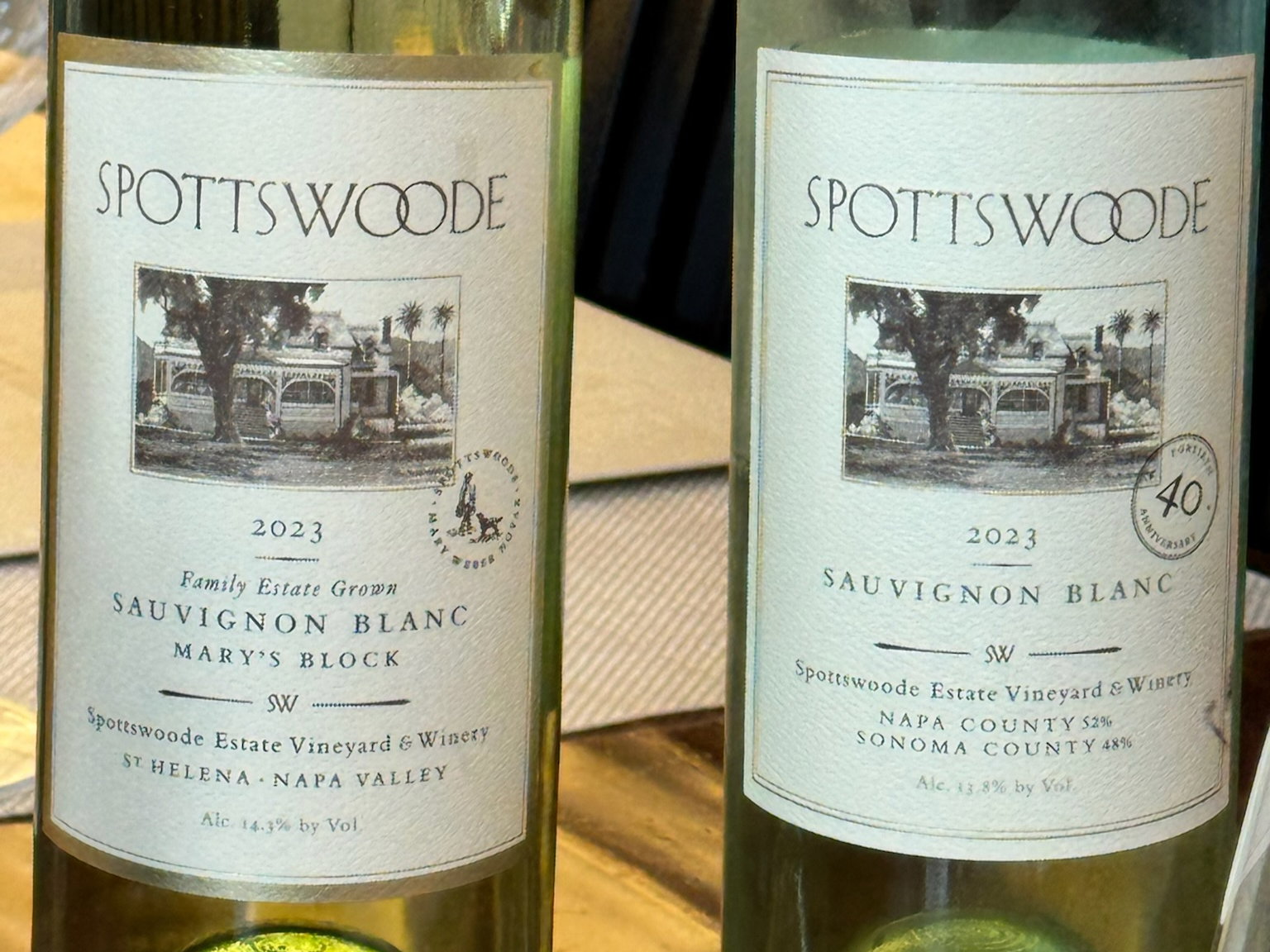 Two bottles of Spottswoode 2023 Sauvignon Blanc displayed, labels featuring a house illustration. Text mentions Napa and Sonoma counties.