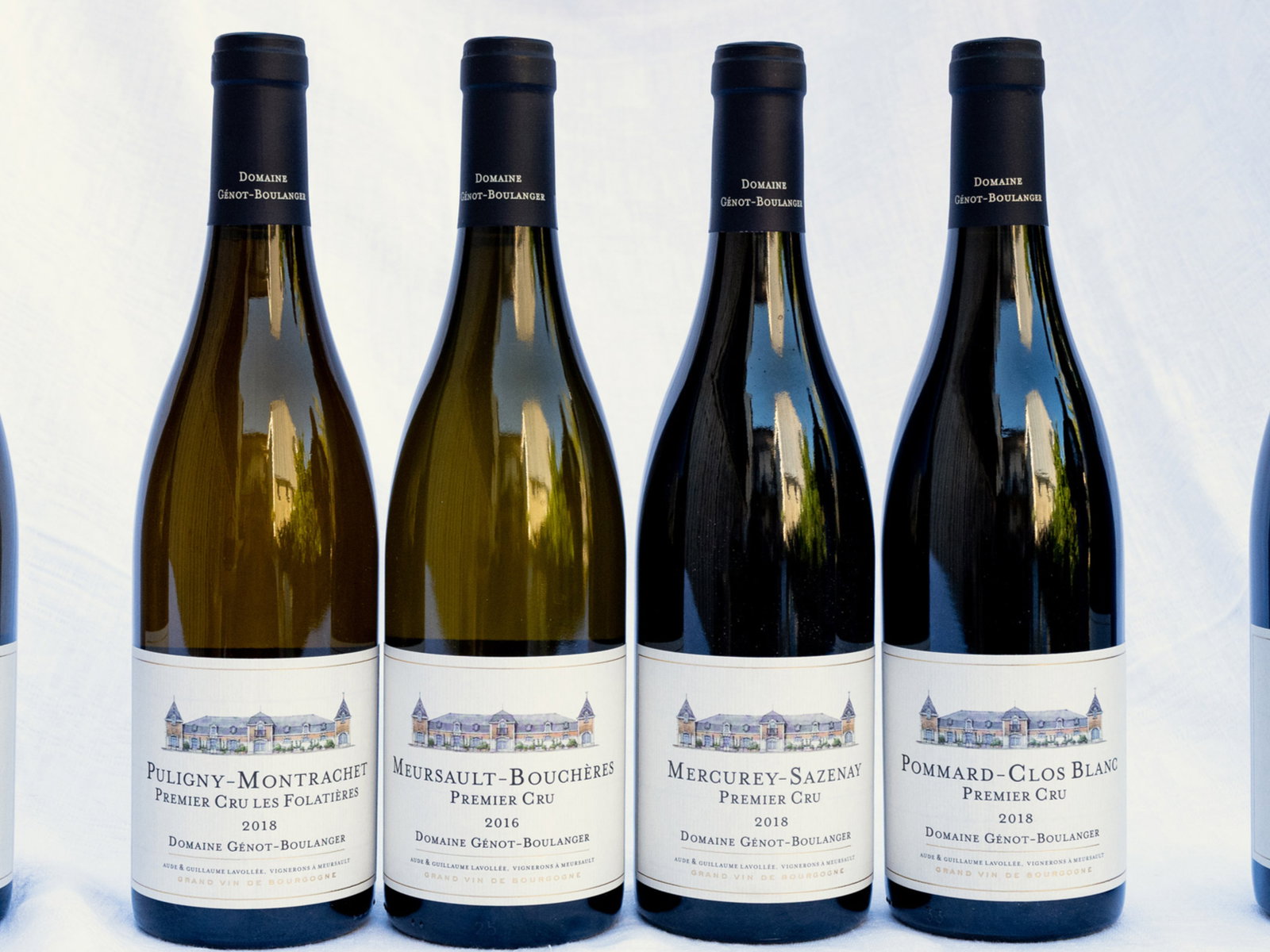 Four wine bottles with labels reading Domaine Génot-Boulanger Premier Cru, against a white background. The image conveys elegance.