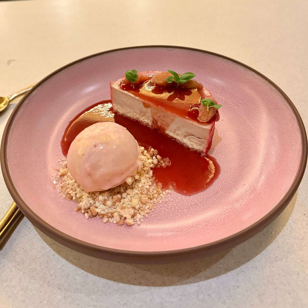 A strawberry sponge dessert plated next to a scoop of ice cream