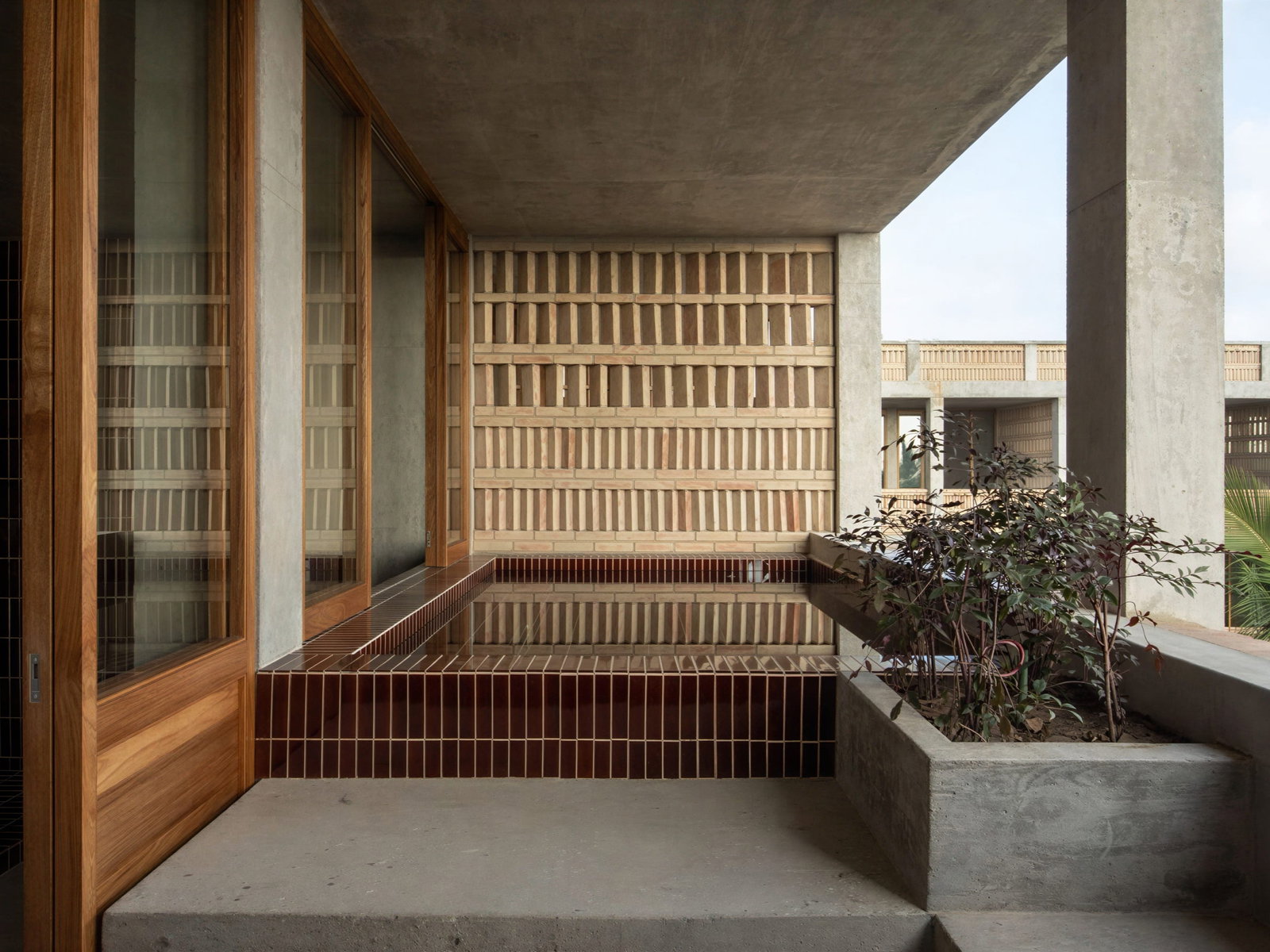 Patio of Ocean View Suite Private Hot Tub at Hotel Humano with wooden accents, a small water feature with tiles, and a planter with leafy plants. Minimalist and serene setting.