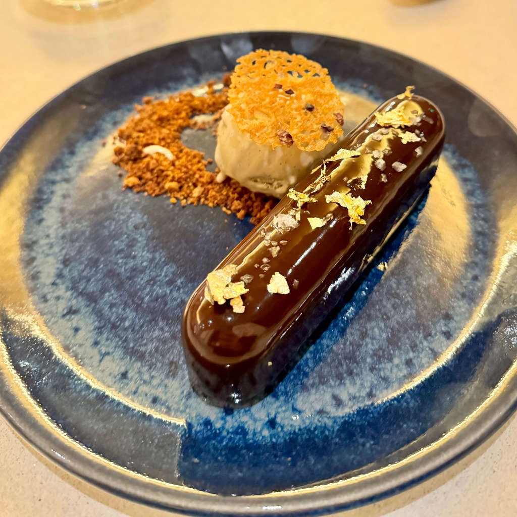 A glazed chocolate bar with gold flakes on a blue plate