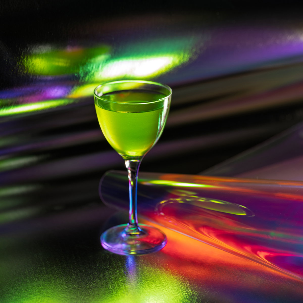 A green drink in a glass on a reflective surface with vibrant holographic colors and patterns, creating a vibrant and lively mood.