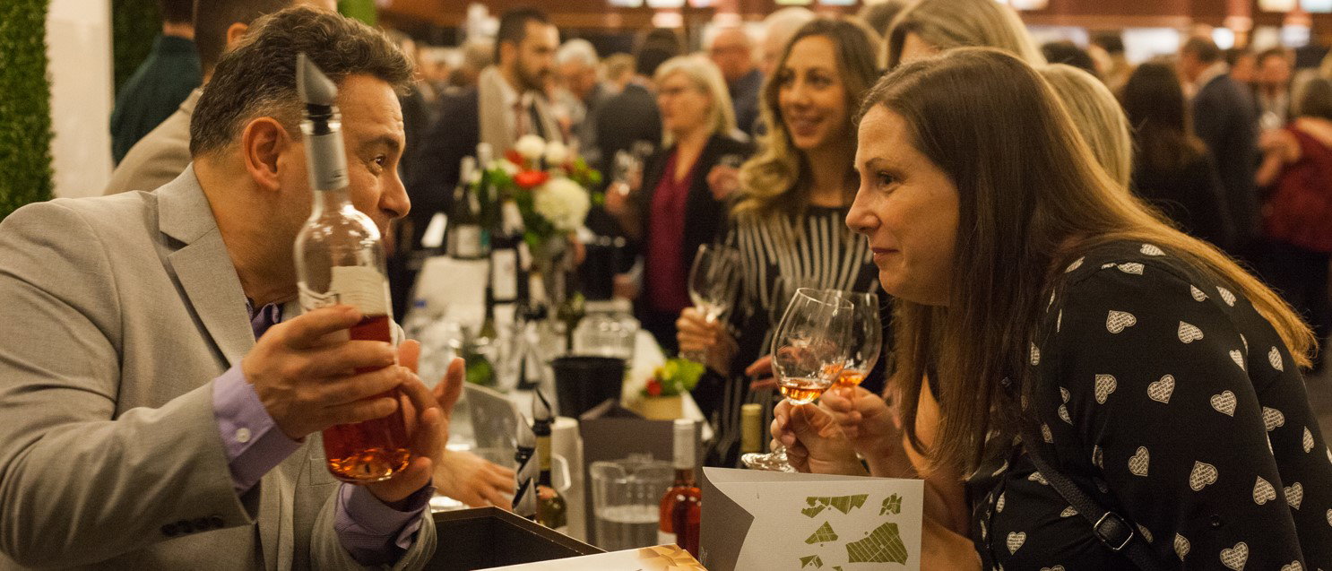A man explains to a woman the intricacies of a wine he just poured at the Vancouver International Wine Festival