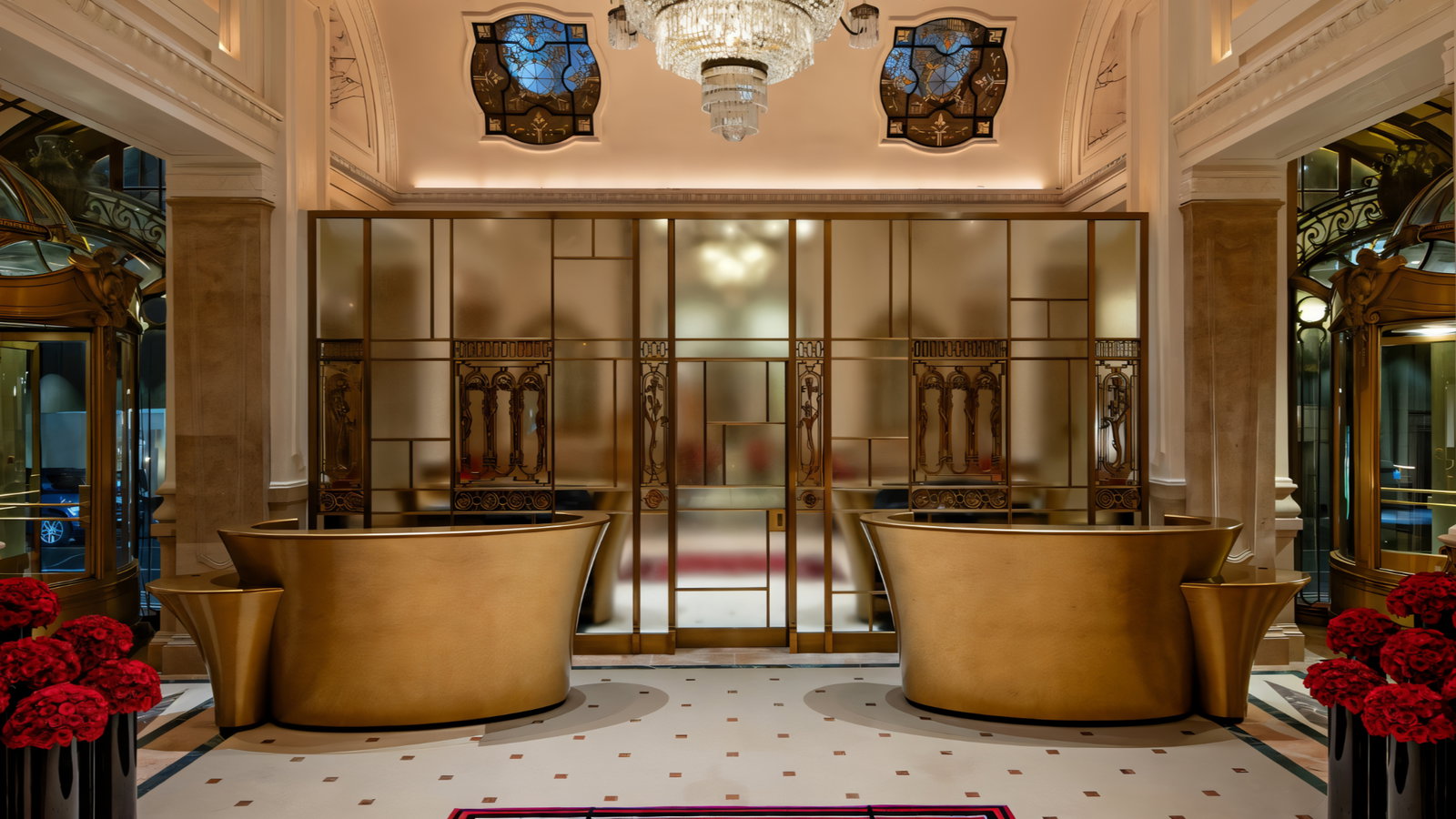 Elegant hotel lobby with gold reception desks, ornate stained glass, a chandelier, and red flowers. Luxurious and sophisticated atmosphere.