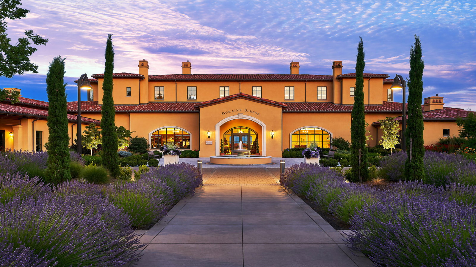 Pathway lined with lavender leads to a two-story building labeled Domaine Serene. The sky is purple and pink, creating a serene mood.