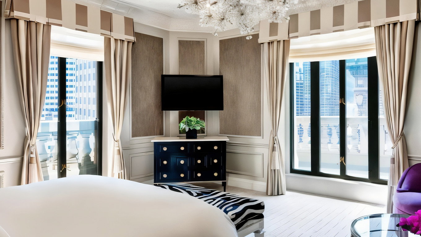 Luxurious bedroom with white bed, zebra-patterned bench, ornate chandelier, TV, and city view through large windows. Elegant, bright decor.