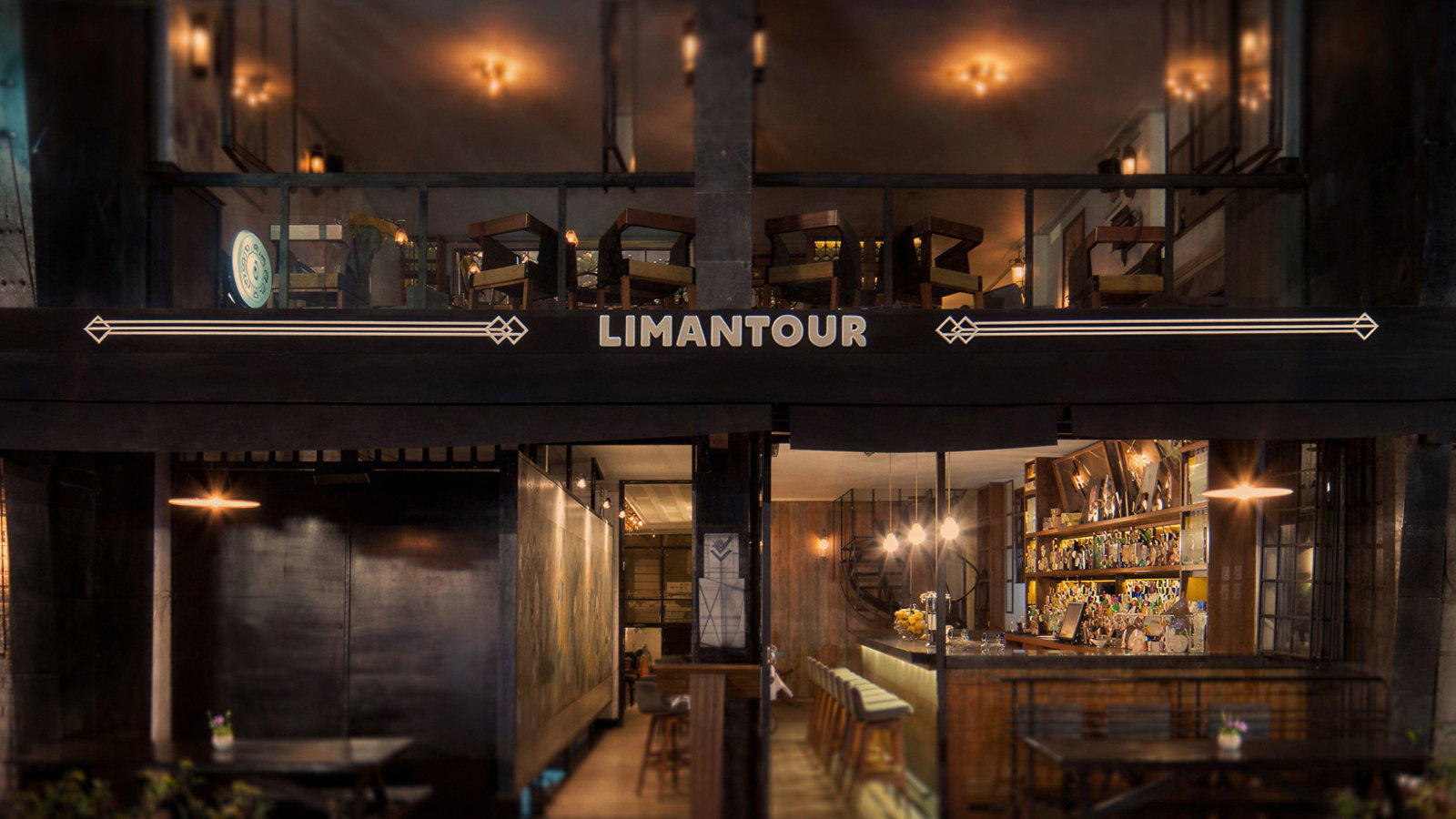 Two-story bar with warm lighting, named Limantour, featuring an outdoor seating area and interior bar, creating a cozy evening ambiance.