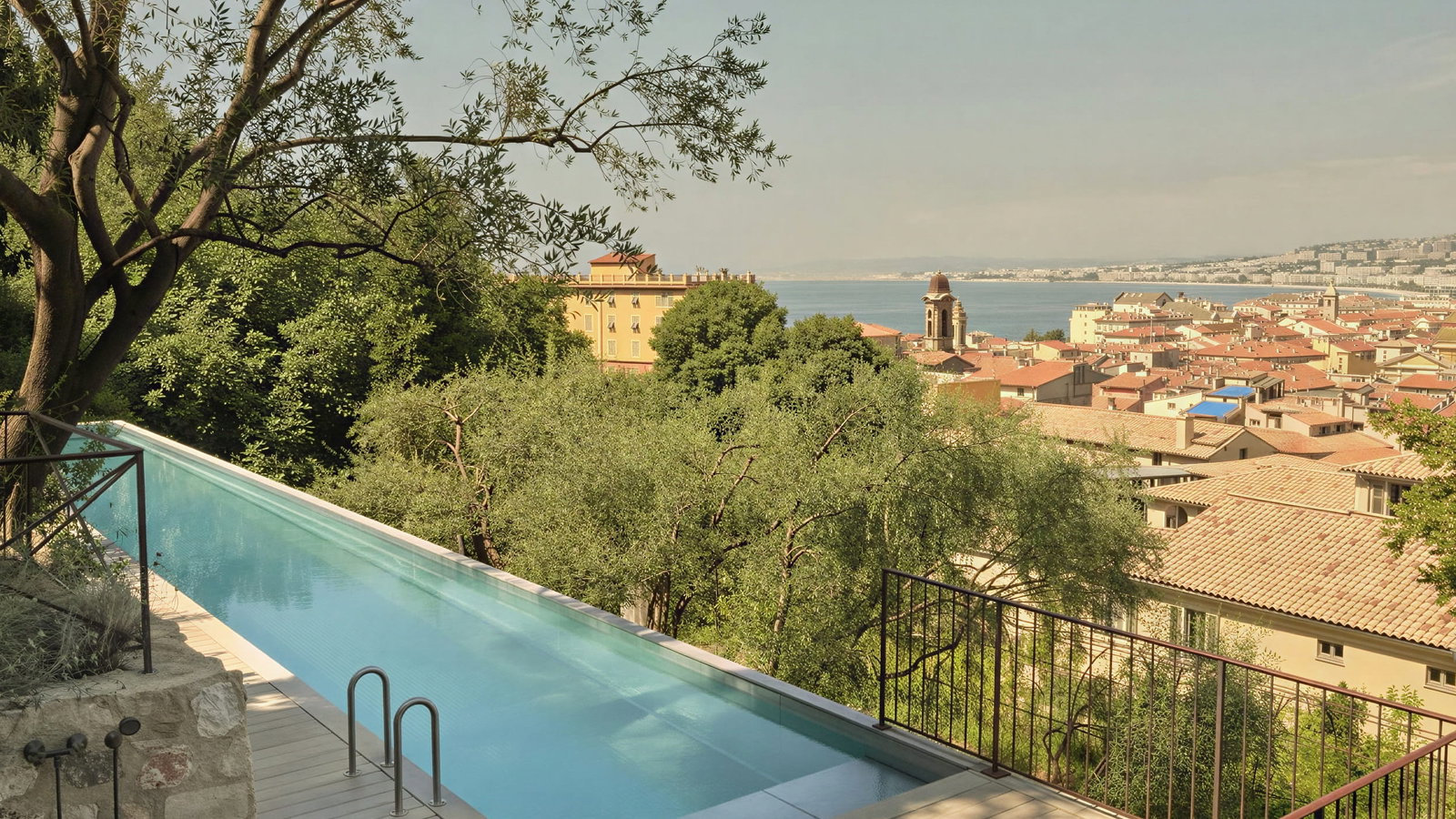 20 meter swimming pool at Hôtel du Couvent overlooking Florence with red-roofed buildings. Trees surround the pool, adding a serene, picturesque vibe.