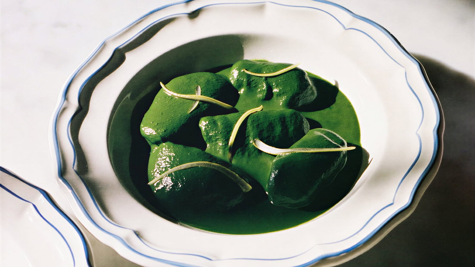 Gnocchi verts, citrons confits du Couvent from Hôtel du Couvent on a white plate with a blue rim, set on a marble surface in bright light.