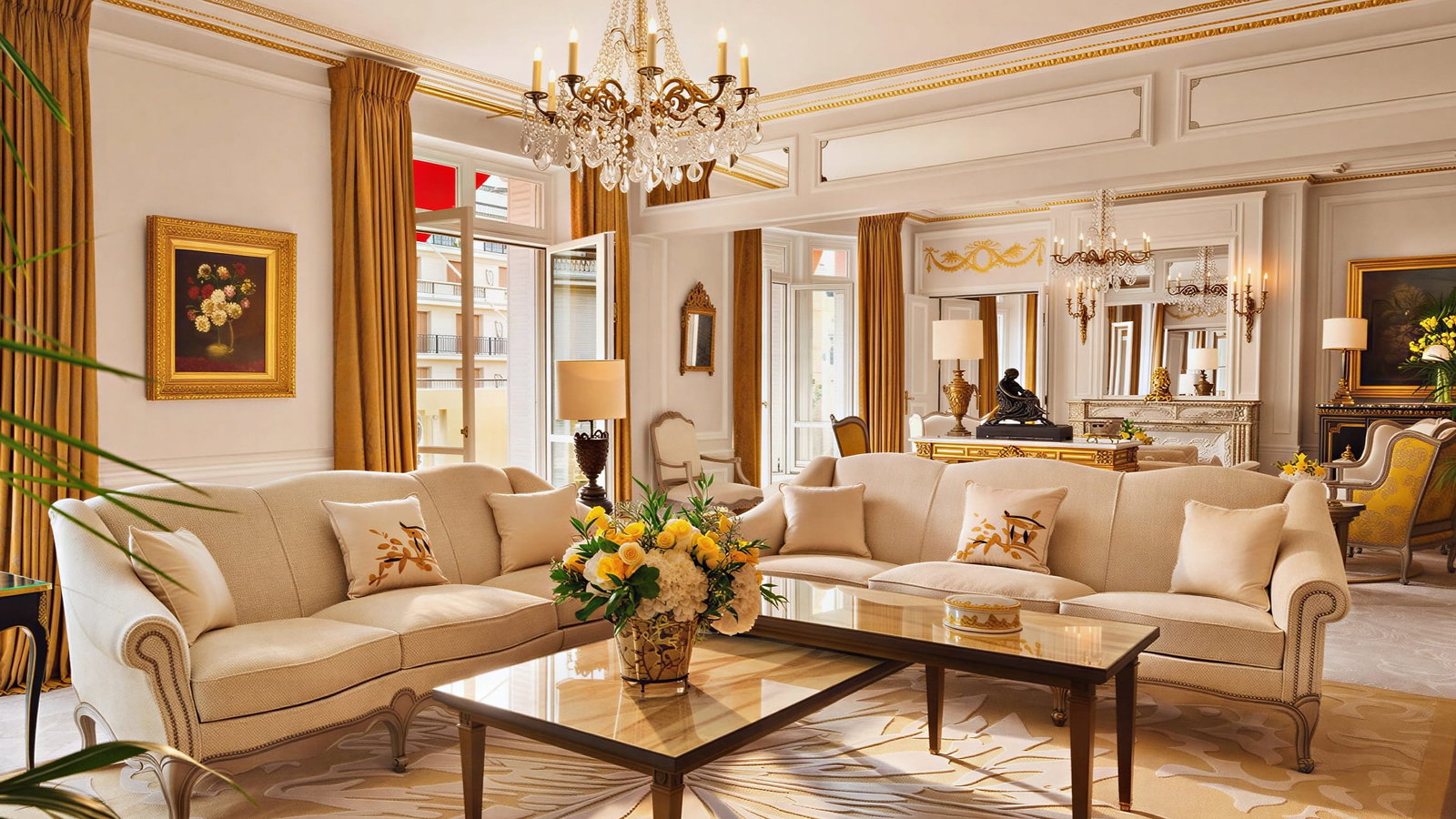 Elegant Royal Suite living room at Hôtel Plaza Athénée with beige sofas, gold curtains, a crystal chandelier, floral painting, and floral arrangement on a glass table. Luxurious decor.