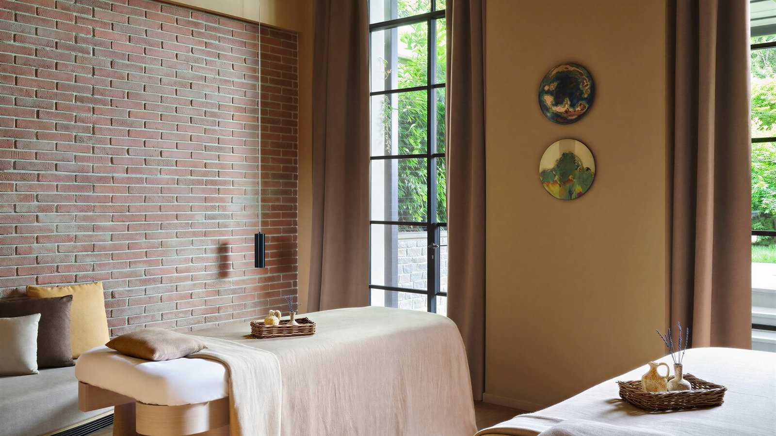 Massage treatment room at Collegio alla Querce spa with beige linens in a serene room with brick wall, large window, and soft lighting. Calm and relaxing atmosphere.