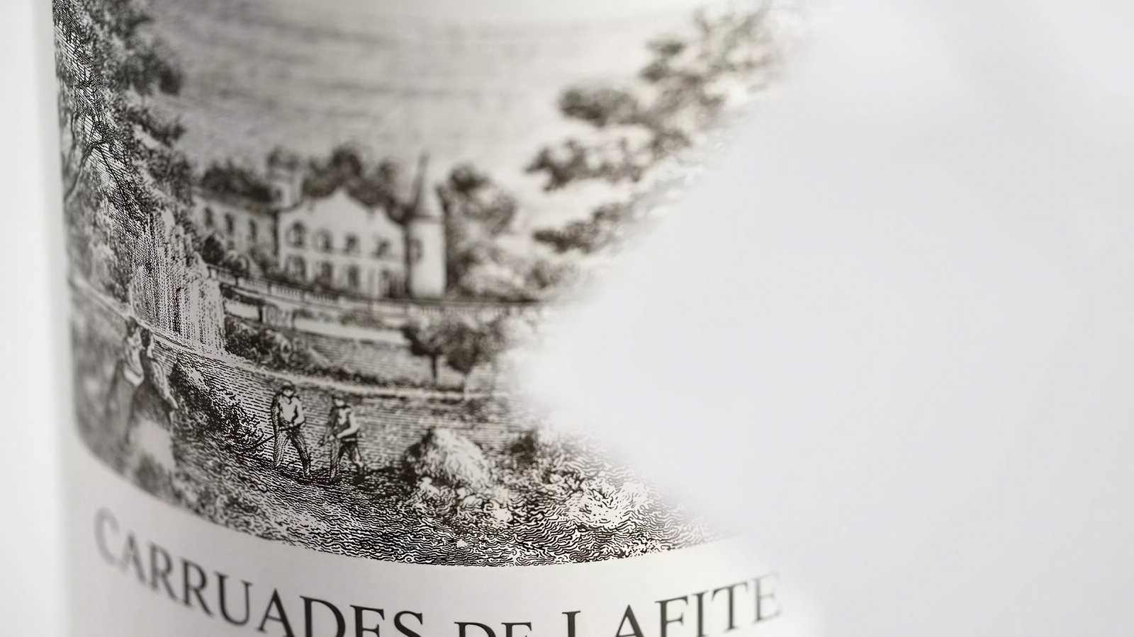 Wine bottle with vintage-style label showing a vineyard scene. Text reads "Carruades de Lafite 2020 Pauillac." Background is blurred white.