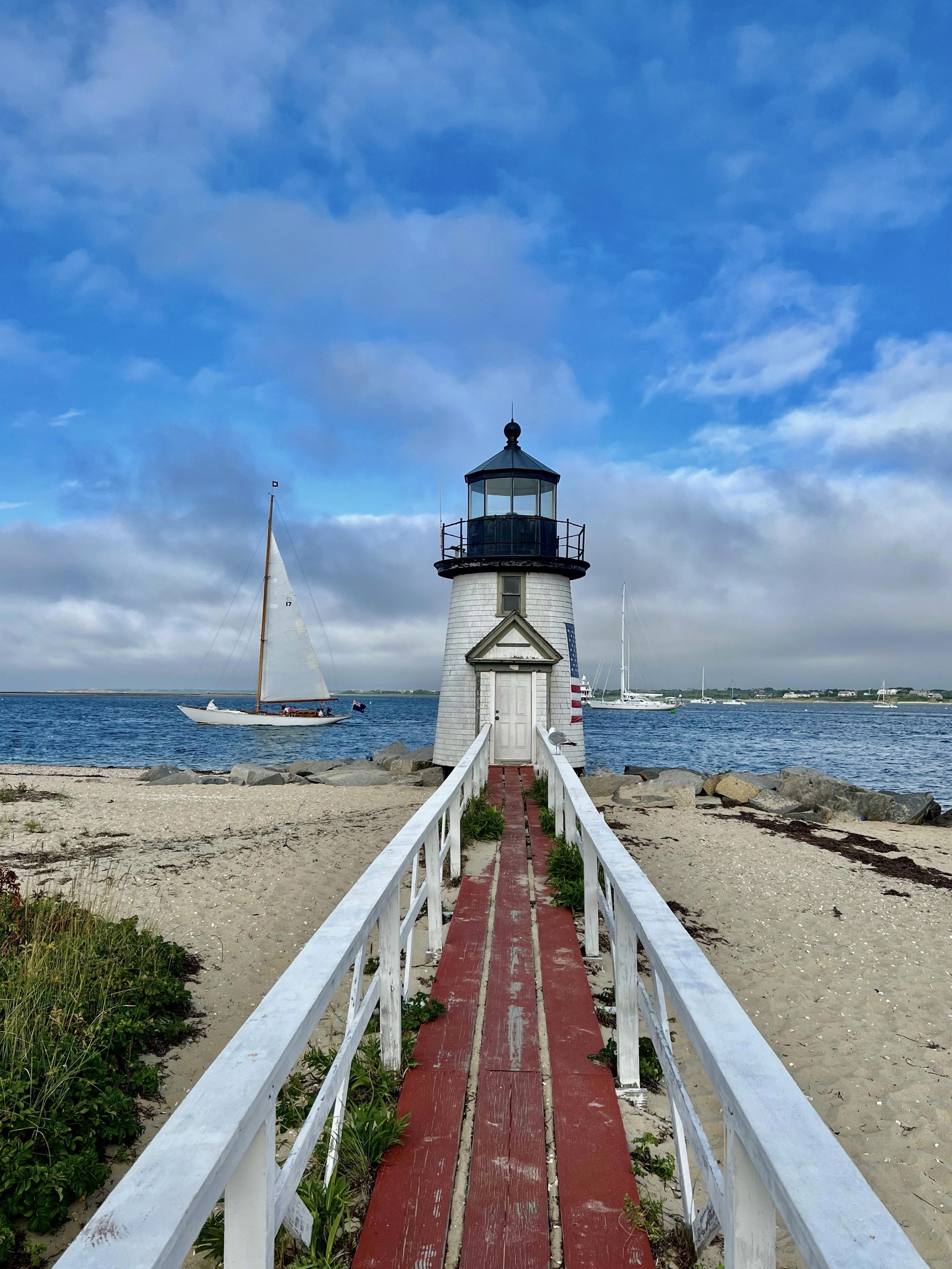 A lighthouse with sailboats in the background