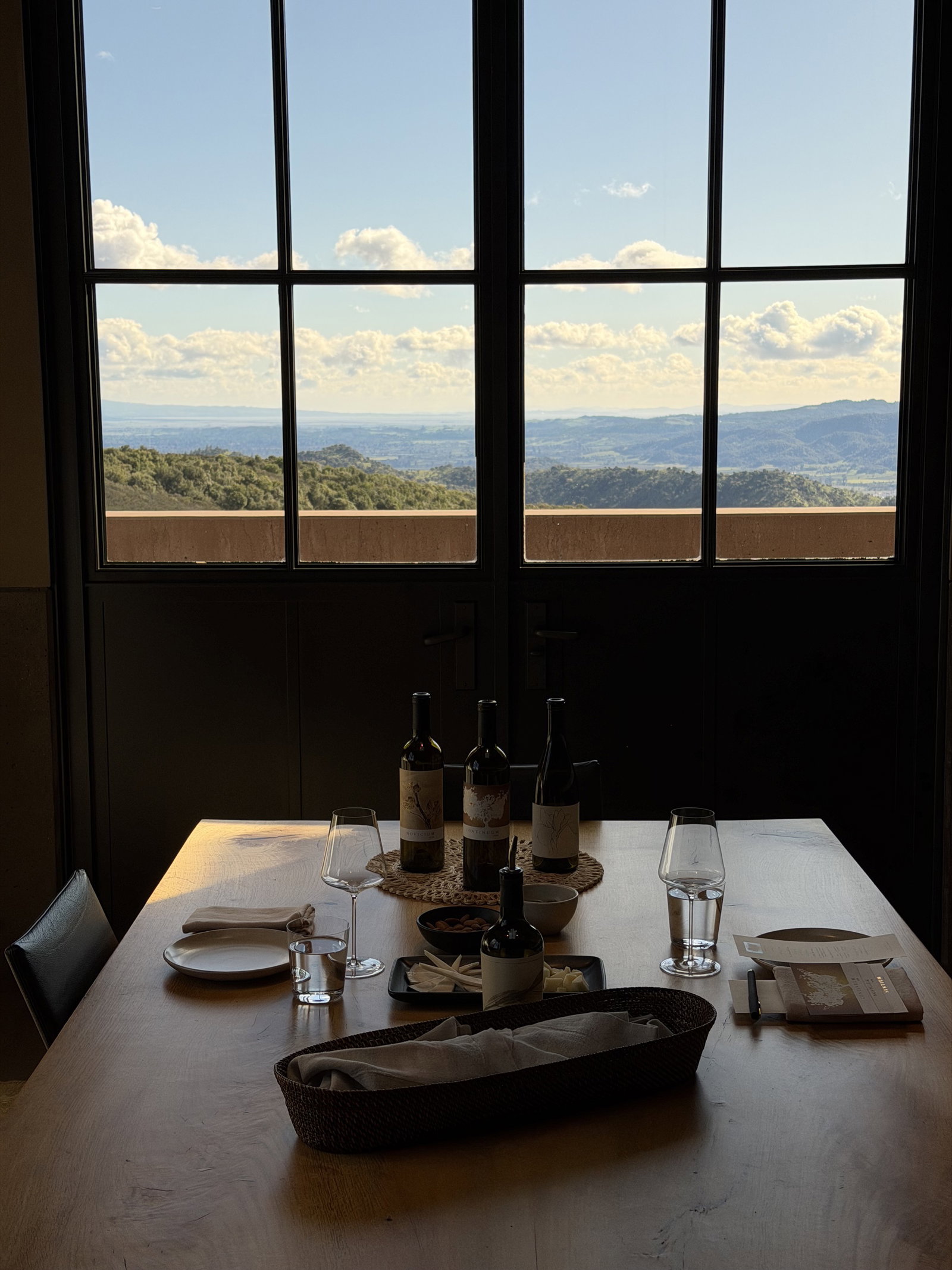 Continuum Estate bottles on a tasting table in front of a window overlooking Napa Valley
